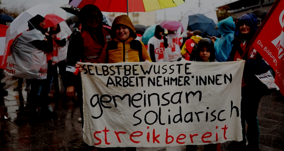 streikende Lehrerin mit Sohn halten Transparent "Selbstbewußte Arbeitnehmer*innen gemeinsam solidarisch streikbereit"