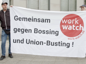 Drei Personen mit Transparent "Gemeinsam gegen Bossing und Union-Busting"