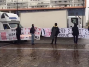 sieben Personen halten große Transparente und blockieren die Zufahrt von LKW