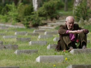 Sohn eines der in Treuenbrietzen von der Wehrmacht ermordeten Italienischen Kriegsinternierten sitzt auf dem Friedhof vor dem Grab seines Vaters