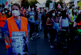 Demonstration von Krankenhausarbeiter_innen, eine Pflegerin im Vordergrund trägt ein Schild mit der Aufschrift: "Ich reanimiere deine Mutter"