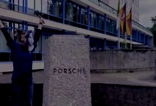 Sockel ohne Büste mit Aufschrift Porsche daneben Frau mit Hammer in Siegespose